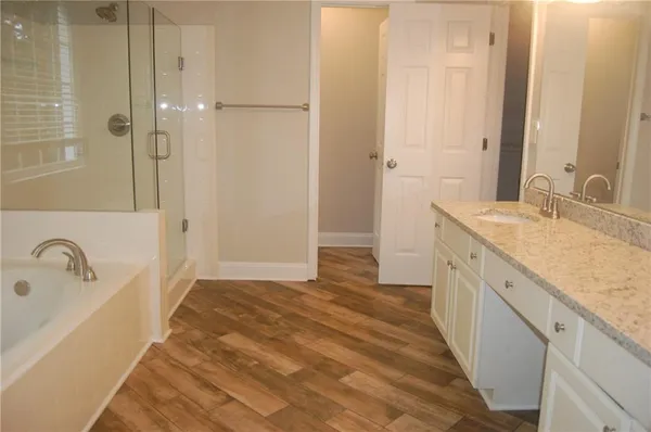 a bathroom with a granite countertop sink a mirror and shower