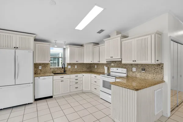 a kitchen with stainless steel appliances kitchen island granite countertop a table chairs sink and cabinets
