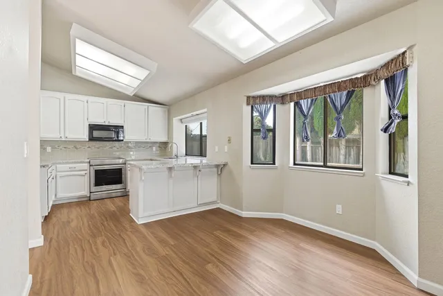 a large kitchen with cabinets wooden floor and stainless steel appliances