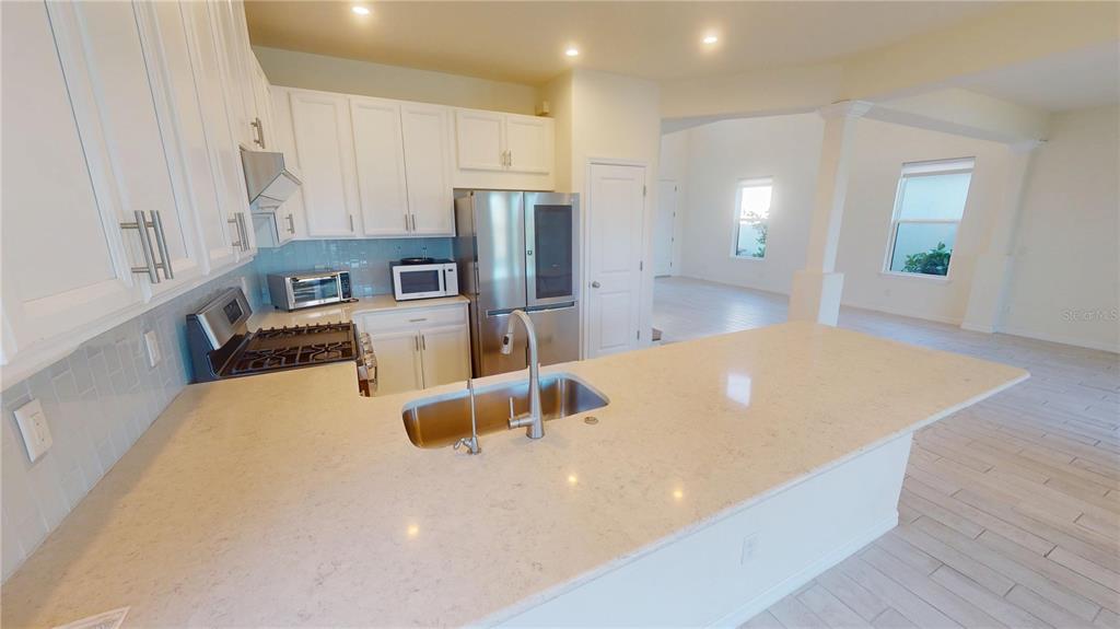 5521 Summit Glen Bradenton, FL 34203 - Photo 26 of 54 a kitchen with stainless steel appliances a refrigerator a sink a stove and white cabinets with wooden floor