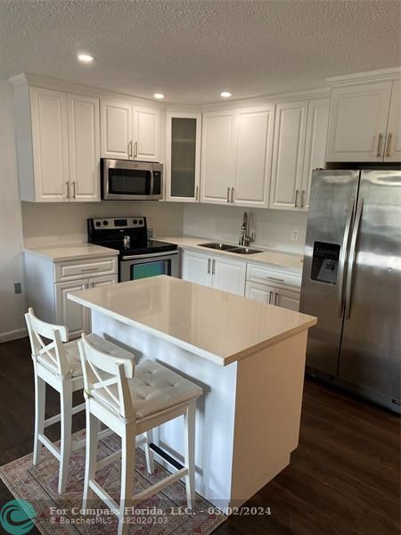 a kitchen with stainless steel appliances kitchen island granite countertop a table chairs microwave and sink