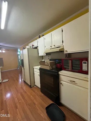 a kitchen with granite countertop white cabinets and refrigerator