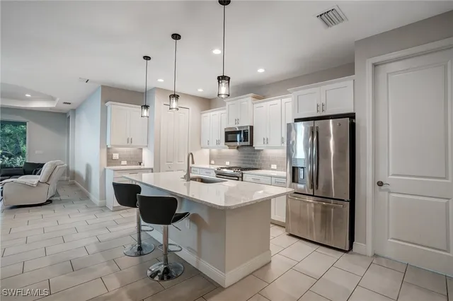 a kitchen with stainless steel appliances kitchen island granite countertop a refrigerator a stove a sink and white cabinets