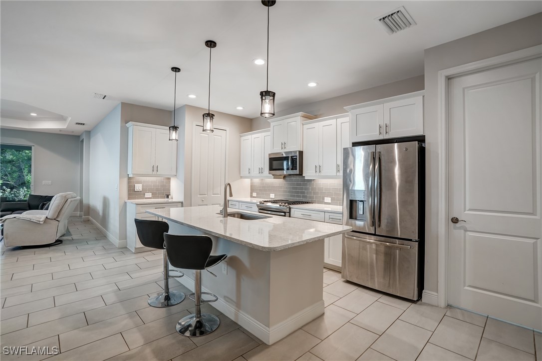 7028 Mistral Way Fort Myers, FL 33966 - Photo 13 of 37 a kitchen with stainless steel appliances kitchen island granite countertop a refrigerator a stove a sink and white cabinets