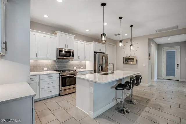 a kitchen with kitchen island granite countertop a sink appliances and cabinets