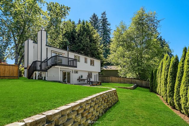 a view of a house with a big yard plants and large trees