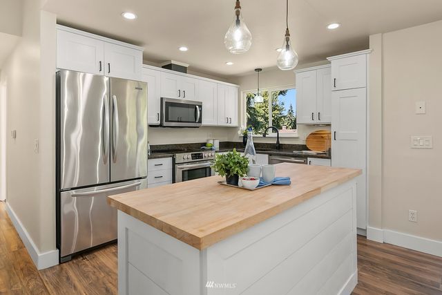 a kitchen with kitchen island a refrigerator and a stove top oven