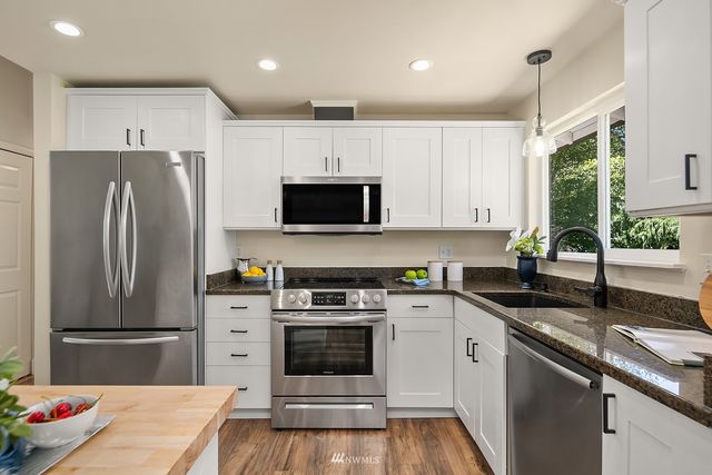 a kitchen with a sink stainless steel appliances and white cabinets