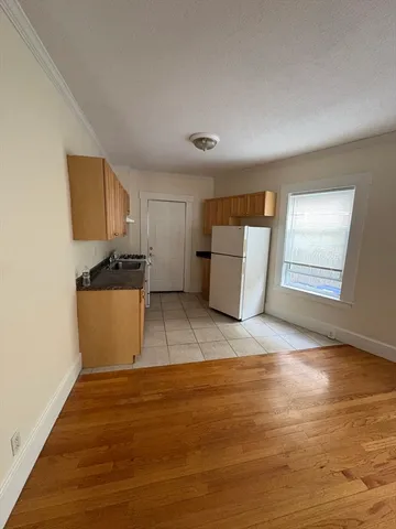a view of kitchen and empty room with wooden floor