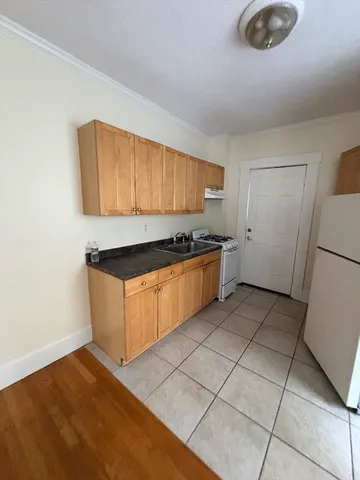 a view of a refrigerator in kitchen and an empty room