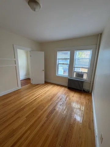 a view of an empty room with wooden floor and window