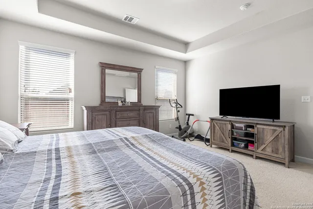 a bedroom with bed a flat tv screen and a large window