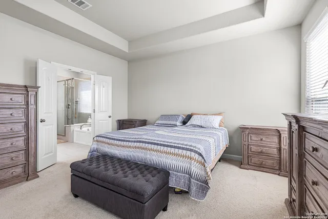 a spacious bedroom with a bed and dresser