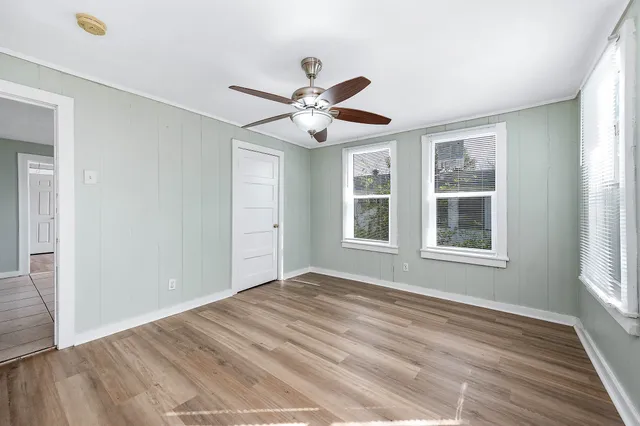 a view of an empty room with a window and wooden floor