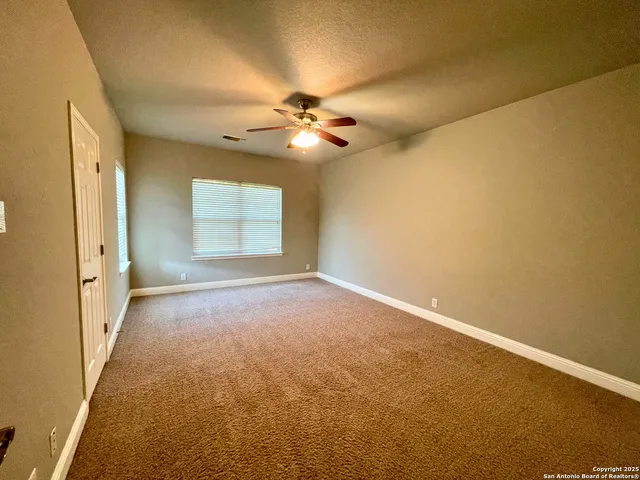 an empty room with windows and fan