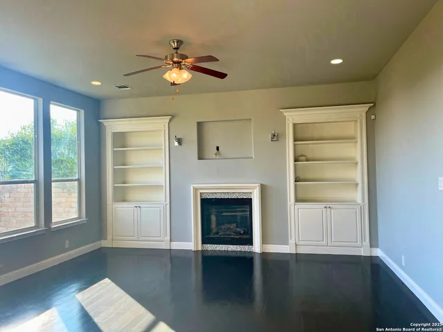 a view of an empty room with wooden floor fireplace and a window