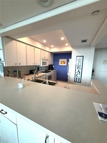 a open kitchen with stainless steel appliances granite countertop a refrigerator a sink and a stove