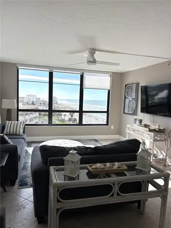 a living room with furniture a flat screen tv and a floor to ceiling window