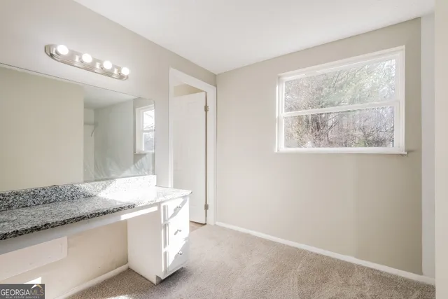a spacious bathroom with a granite countertop sink and a mirror
