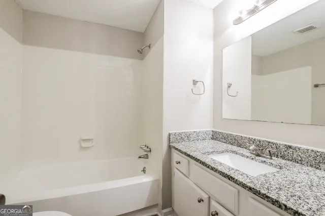 a bathroom with a granite countertop bathtub shower sink and mirror