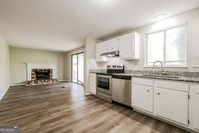 a kitchen with granite countertop a stove a sink and a refrigerator
