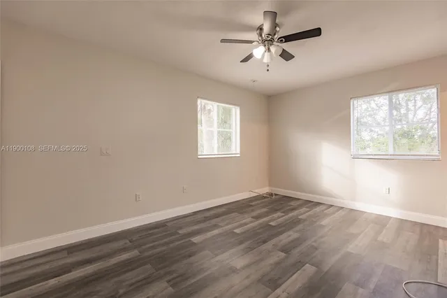 an empty room with wooden floor fan and windows