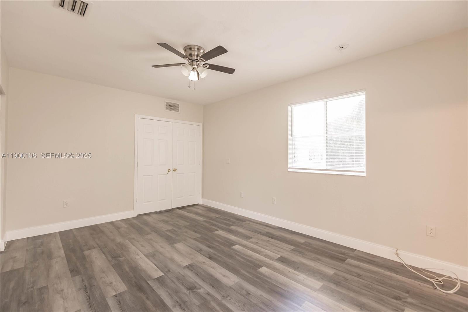 8297 Southwest 25th Court, Unit 101 Miramar, FL 33025 - Photo 28 of 42 an empty room with wooden floor fan and windows