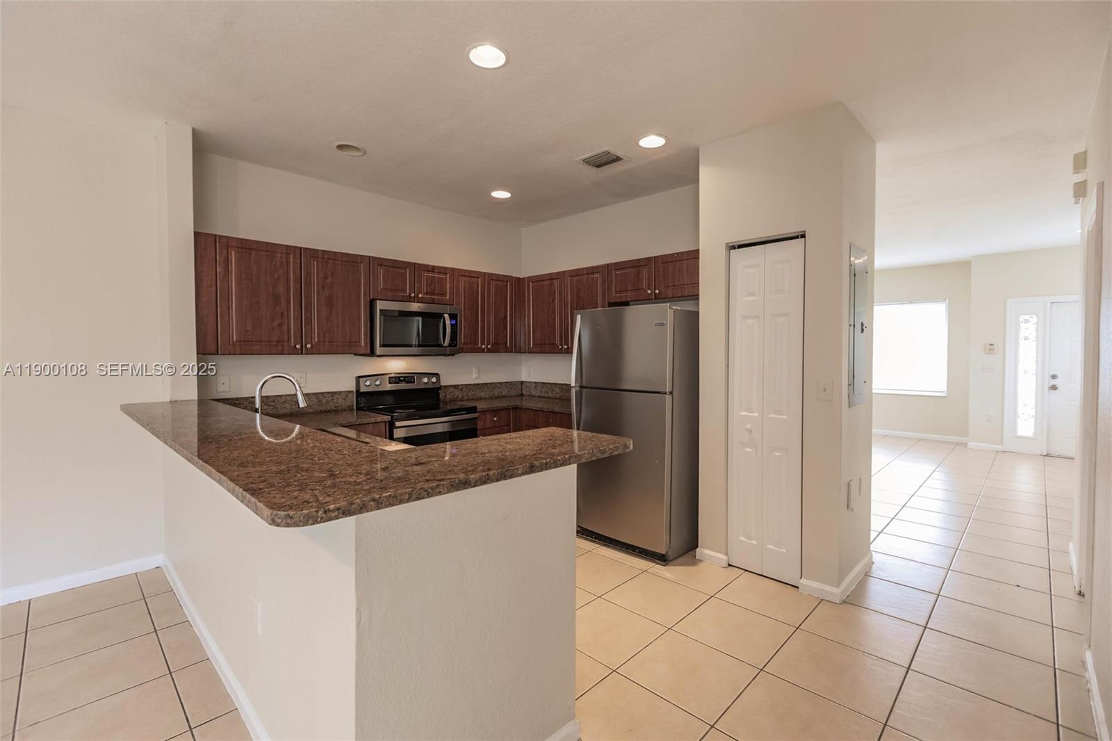 8297 Southwest 25th Court, Unit 101 Miramar, FL 33025 - Photo 9 of 42 a kitchen with stainless steel appliances granite countertop a refrigerator a stove a sink and a microwave