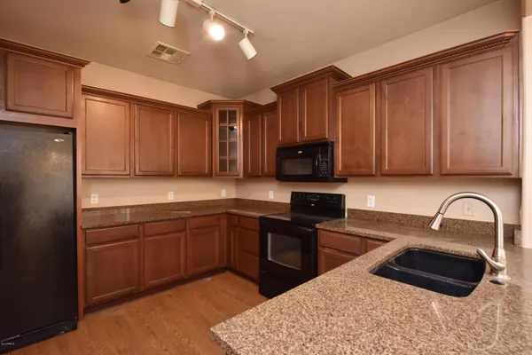 a kitchen with granite countertop a sink cabinets and stainless steel appliances
