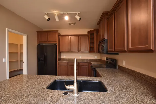 a kitchen with stainless steel appliances granite countertop a sink and a refrigerator