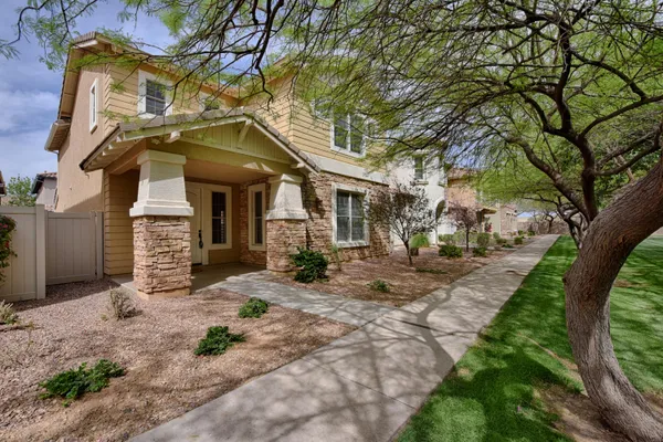 a view of a house with brick walls plants and large tree