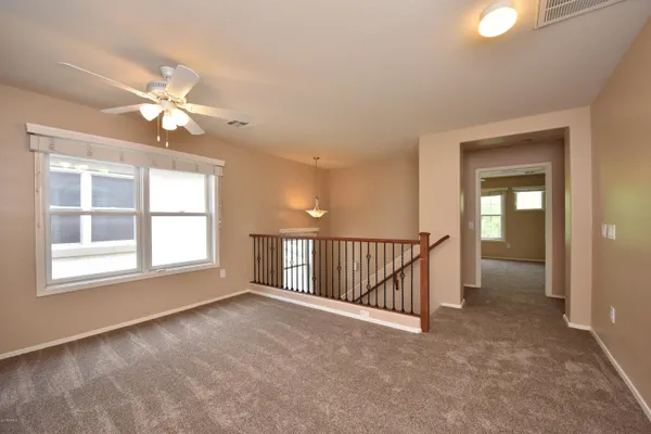 an empty room with chandelier fan and windows