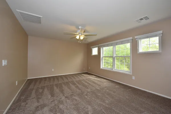 an empty room with windows and chandelier fan