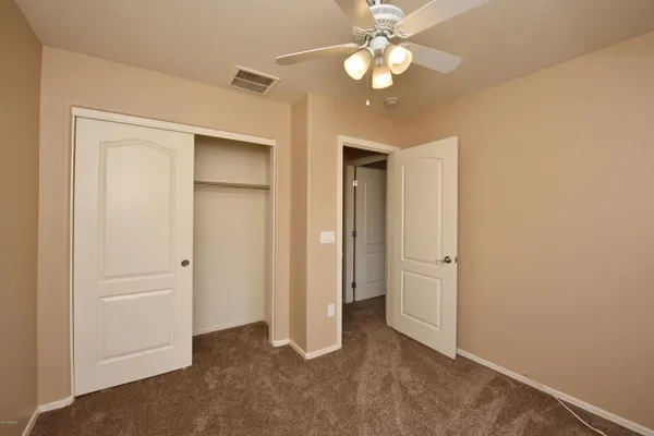 an empty room with closet and a ceiling fan