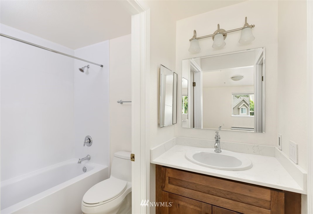 19410 Bothell Way Northeast, Unit D301 Bothell, WA 98011 - Photo 11 of 18 a bathroom with a granite countertop sink toilet a mirror and shower