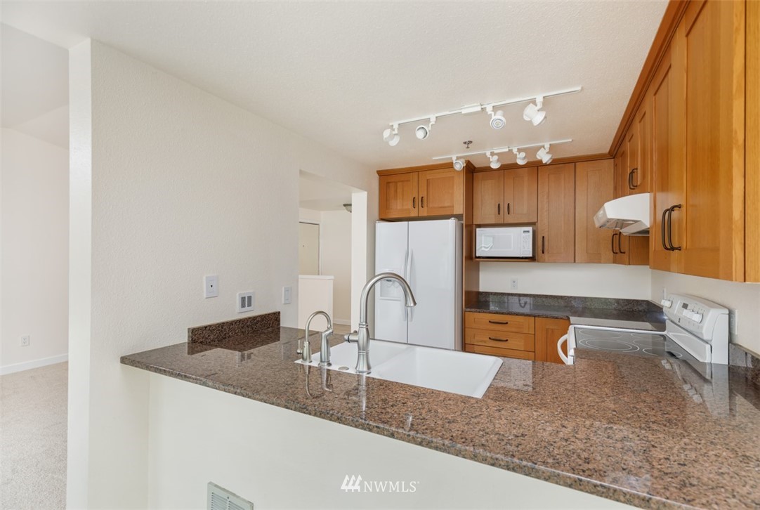 19410 Bothell Way Northeast, Unit D301 Bothell, WA 98011 - Photo 6 of 18 a kitchen with granite countertop a sink and a stove top oven