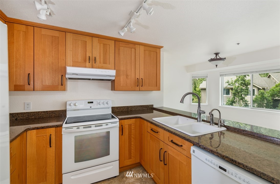 19410 Bothell Way Northeast, Unit D301 Bothell, WA 98011 - Photo 7 of 18 a kitchen with granite countertop a sink stove and cabinets