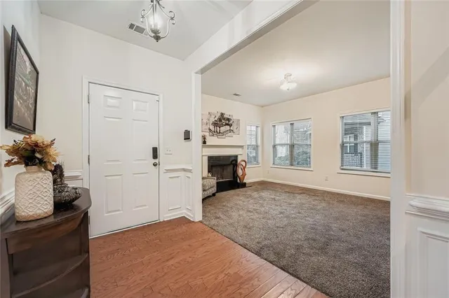 a view of a livingroom with a fireplace a chandelier a wooden floor and windows