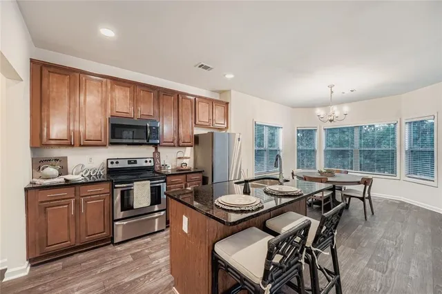 a kitchen with a stove a sink dishwasher a dining table and chairs with wooden floor