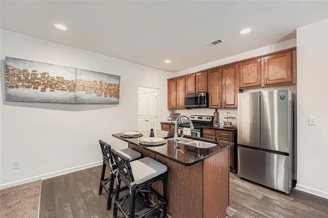 a kitchen with stainless steel appliances granite countertop a refrigerator a stove a sink dishwasher a dining table and chairs