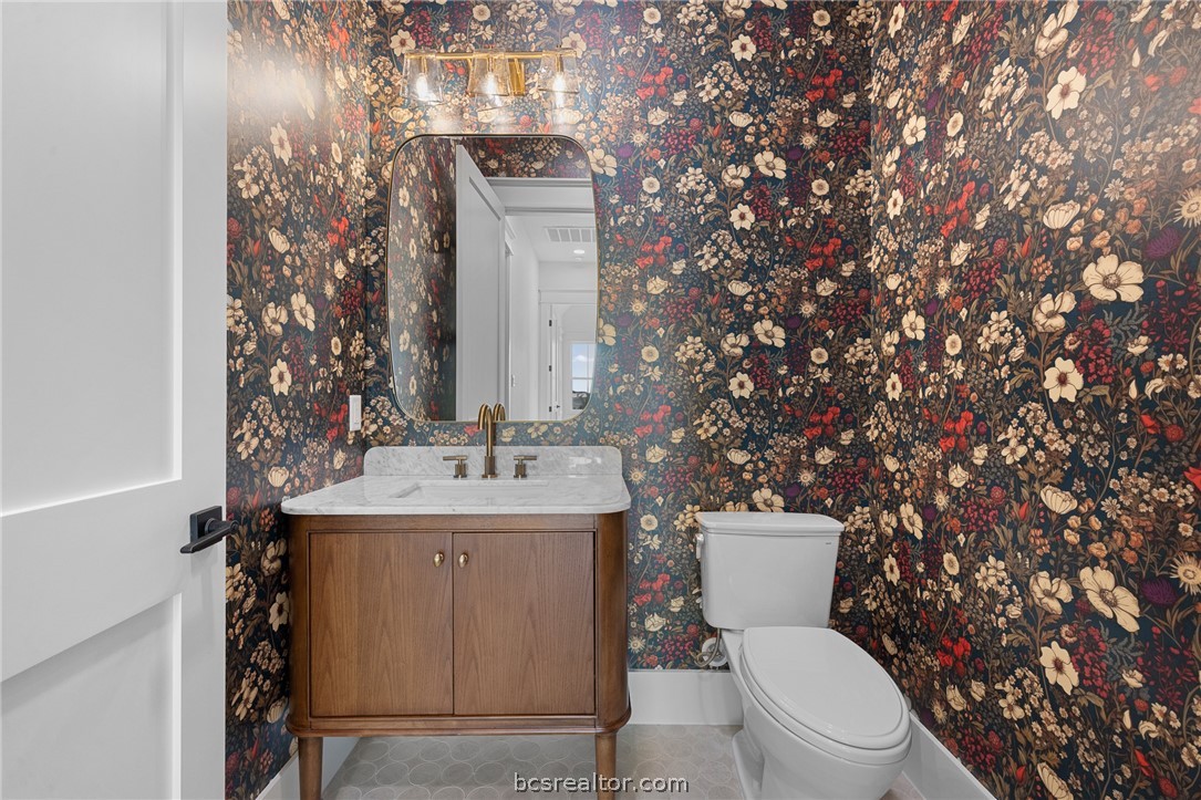 424 Pleasant Hill School Road Brenham, TX 77833 - Photo 14 of 26 The Powder Room has quite the personality with moodier wallpaper that is tastefully balanced with the warm wood tone of the vanity and lighter patterned floor.