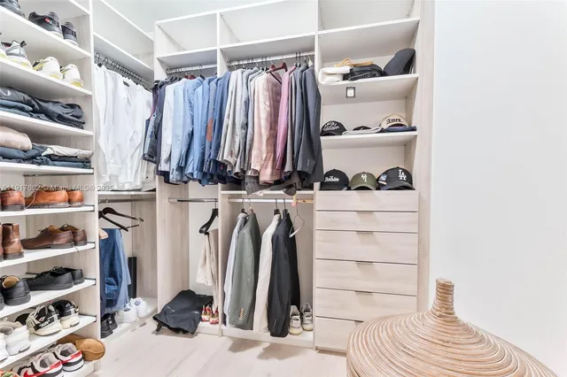 a view of walk in closet with clothes and shoes