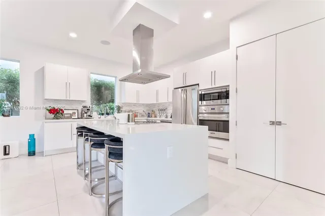 a kitchen with stainless steel appliances kitchen island granite countertop a table chairs and a refrigerator