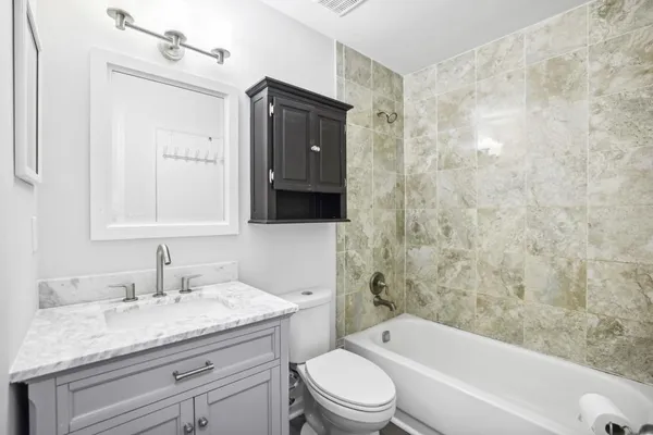 a bathroom with a granite countertop sink a toilet and bathtub