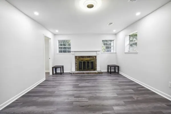 an empty room with wooden floor fireplace and windows