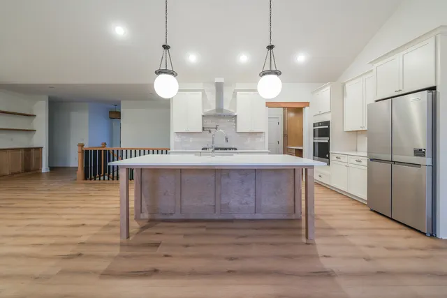 a kitchen with stainless steel appliances granite countertop a refrigerator a sink and a stove