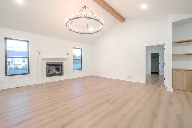 a view of empty room with wooden floor fireplace and window