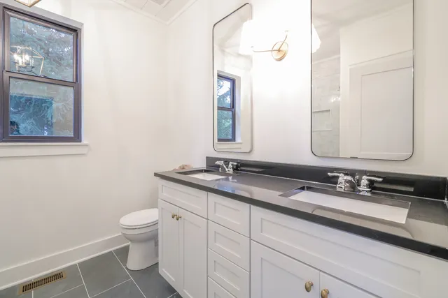 a bathroom with a granite countertop toilet sink and mirror
