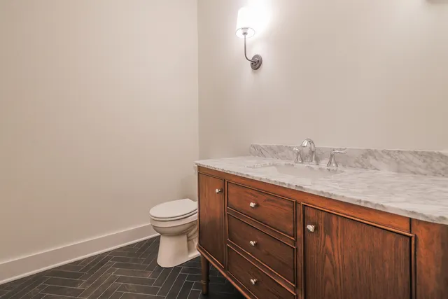 a bathroom with a granite countertop toilet and a sink