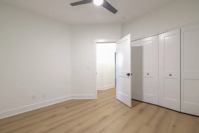 a view of an empty room and wooden floor closet area